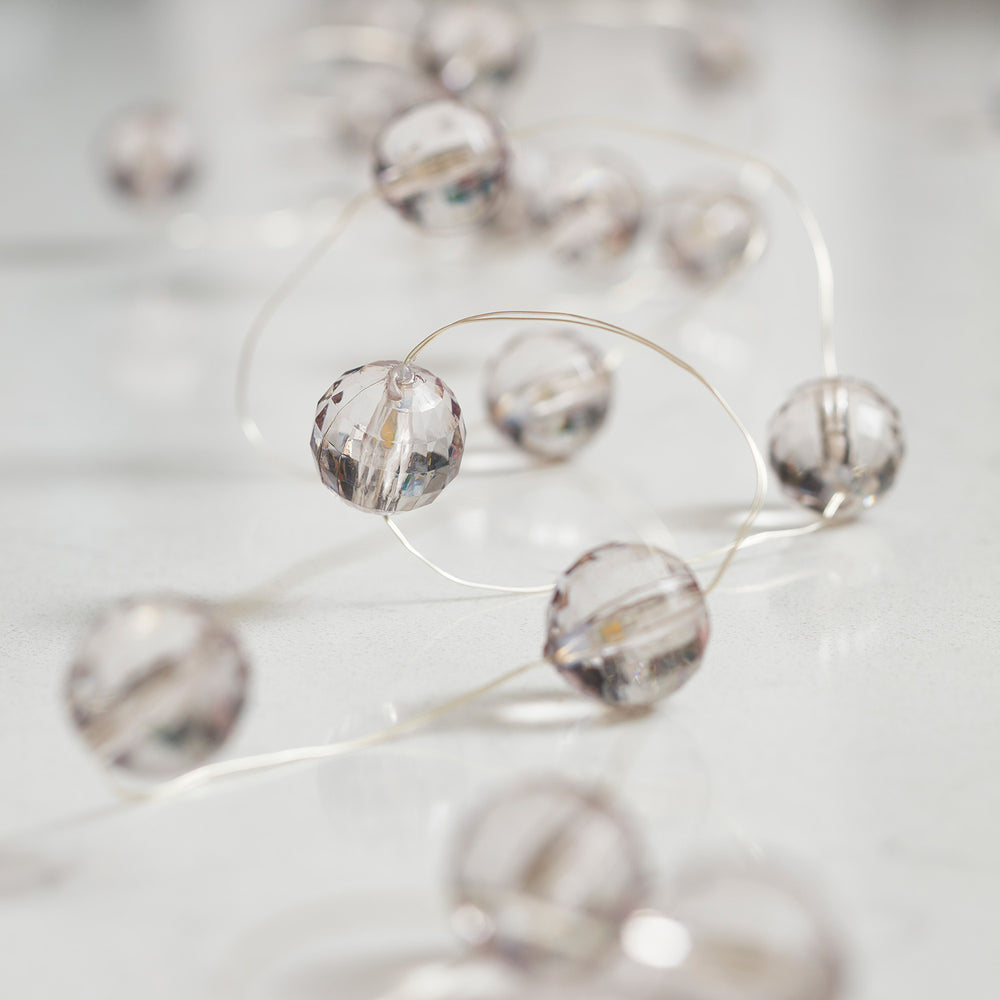 Micro Lichterkette mit transparenten Acrylperlen und warmweißen LEDs auf hellem Tisch liegend