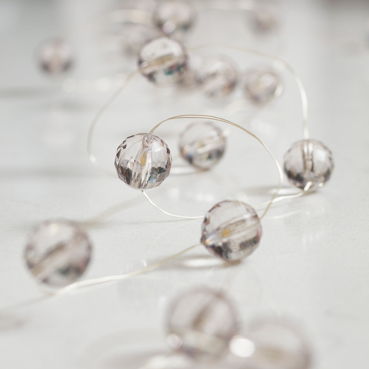 Micro Lichterkette mit transparenten Acrylperlen und warmweißen LEDs auf hellem Tisch liegend