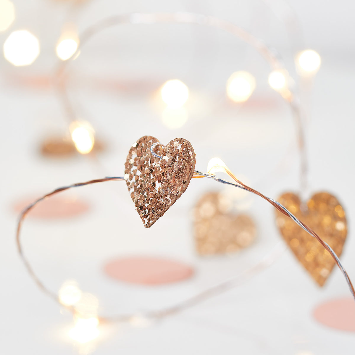 Nahaufnahme einer rosegold glitzernden Herz-LED an einer kupferfarbenen Lichterkette