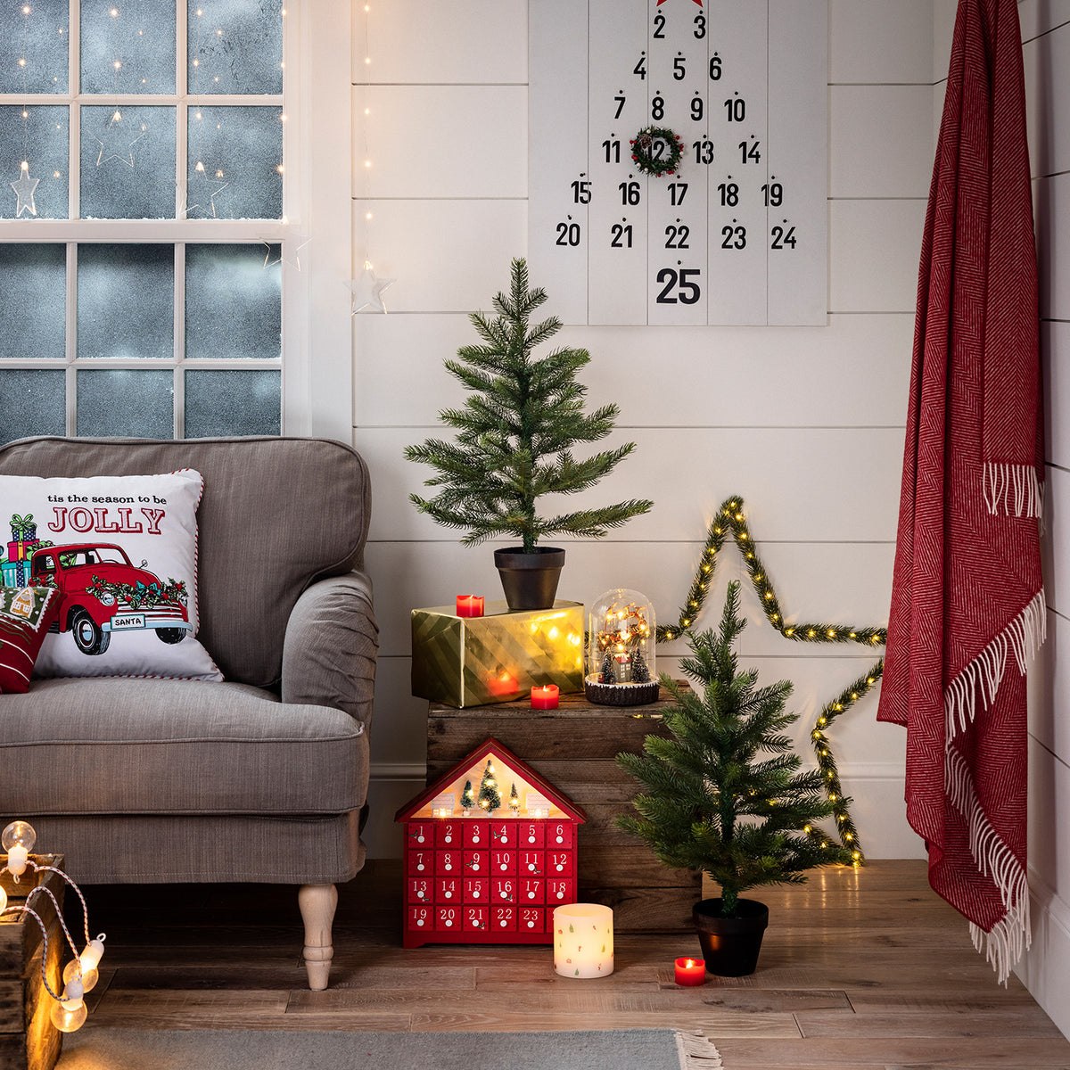 Gemütliche Weihnachtszimmerecke mit Adventskalender, kleinen Tannen und roten LED Votivkerzen