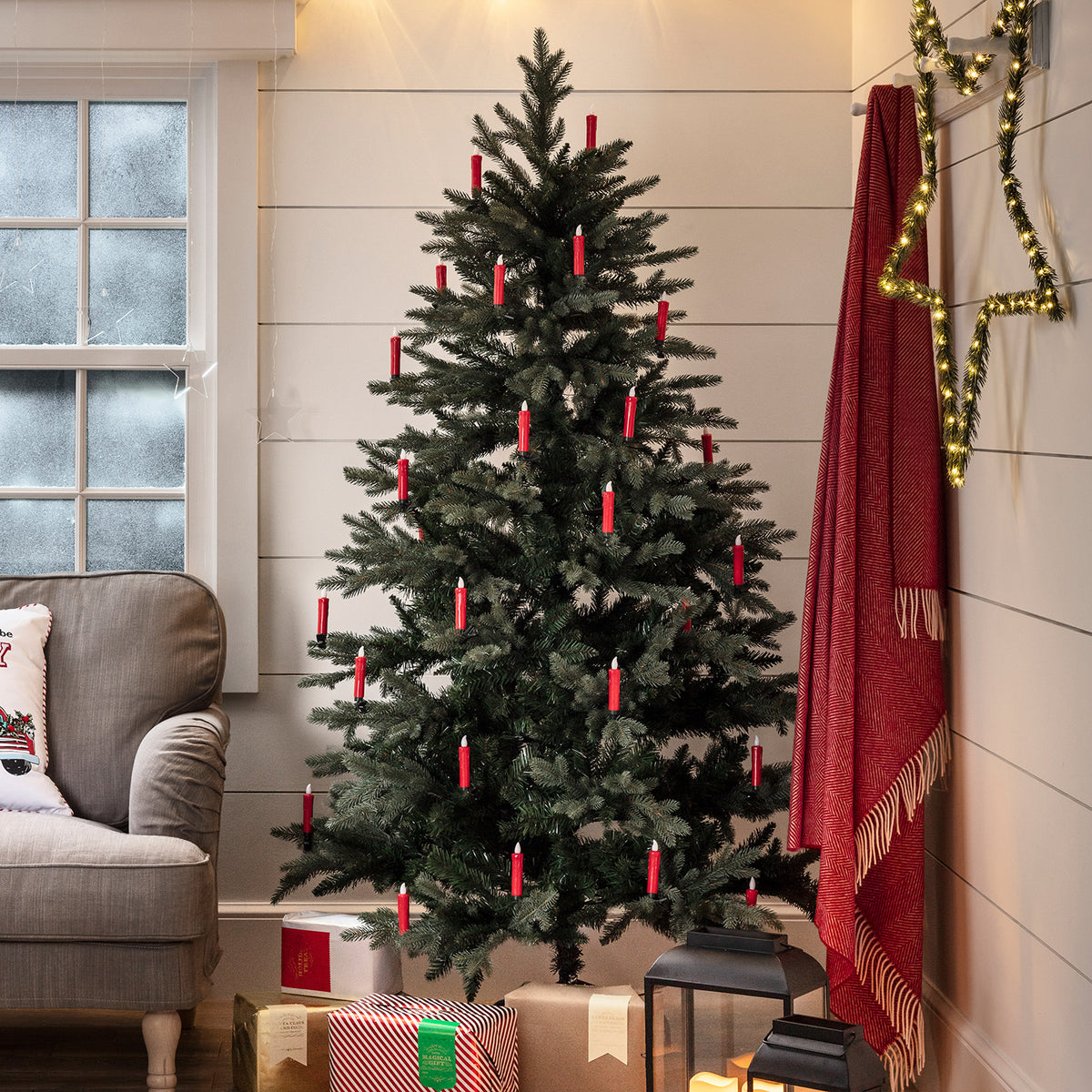 Weihnachtsbaum mit roten LED-Kerzen, daneben rote Decke und beleuchteter Stern an der Wand