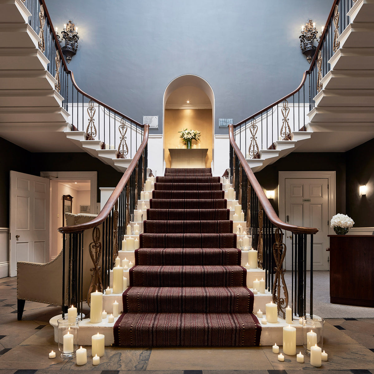 LED Stumpenkerzen säumen einen roten Teppich auf einer Treppe in einem eleganten Innenraum