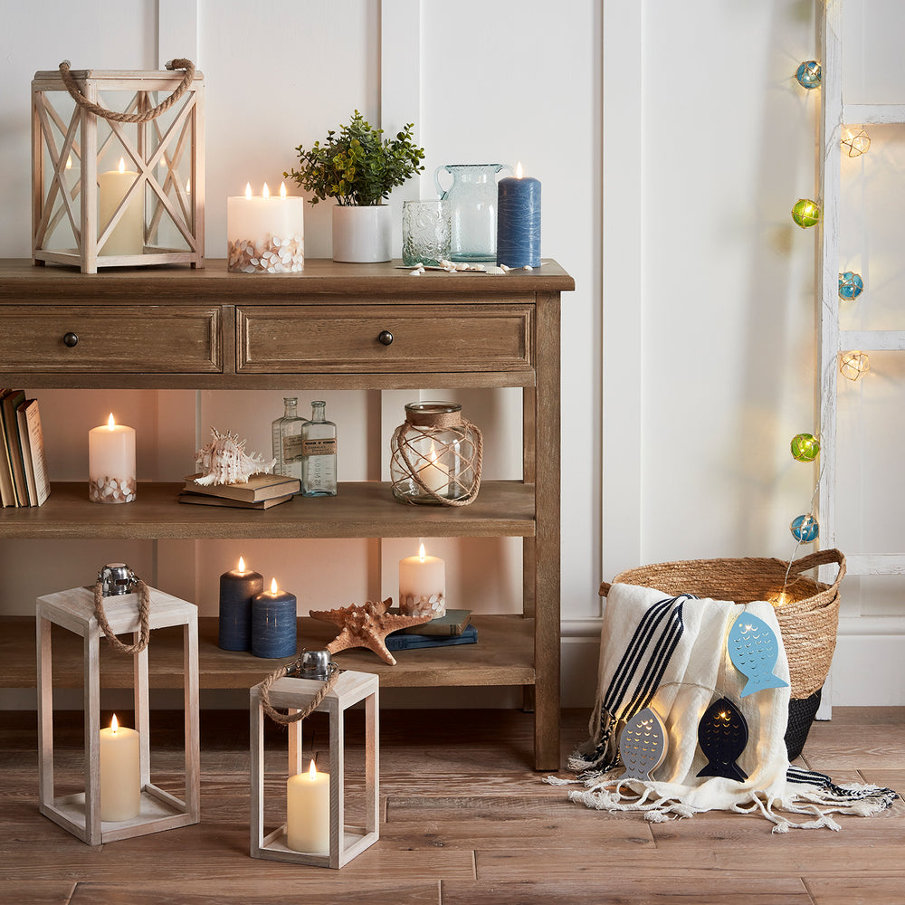 Wohnzimmer mit maritimer Dekoration und mehreren LED Kerzen auf Holzkommode