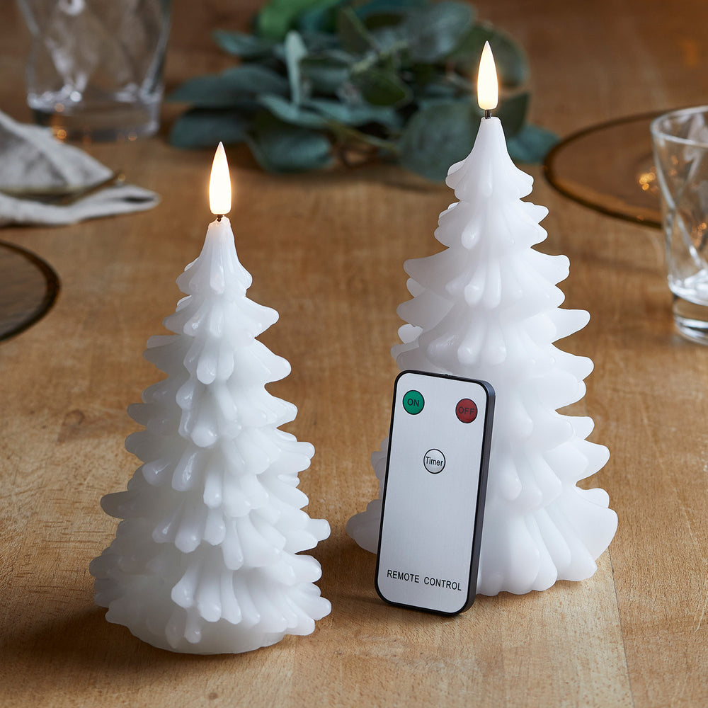 Zwei weiße LED-Kerzen in Form von Weihnachtsbäumen mit Fernbedienung auf Holztisch