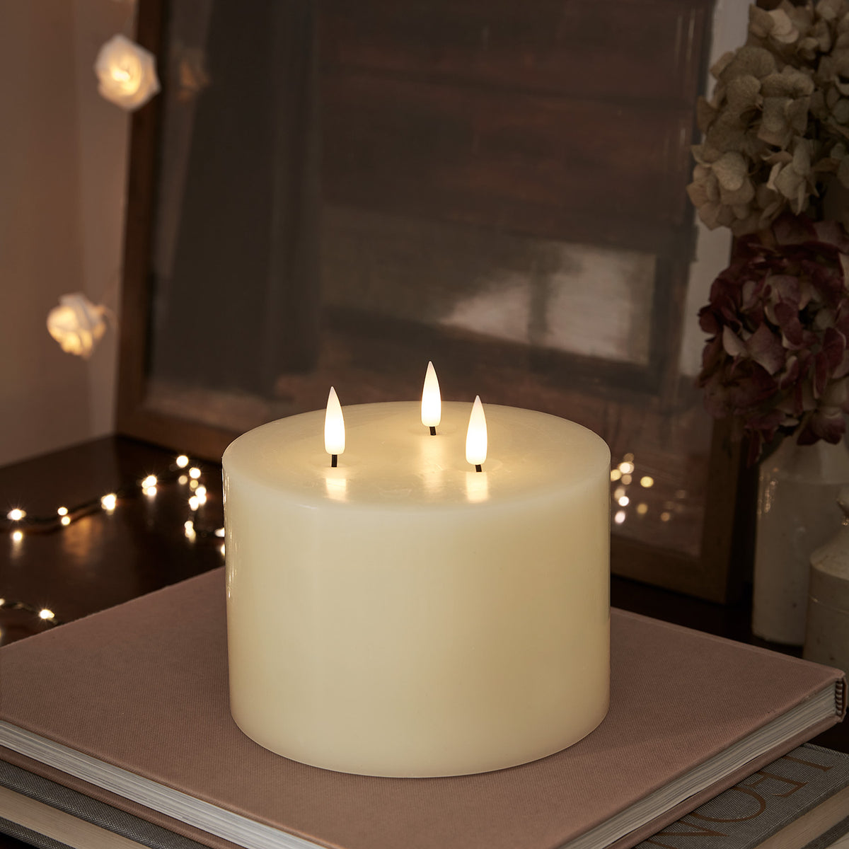 Dreidochtige LED-Kerze mit Fernbedienung auf Tisch mit weihnachtlicher Dekoration