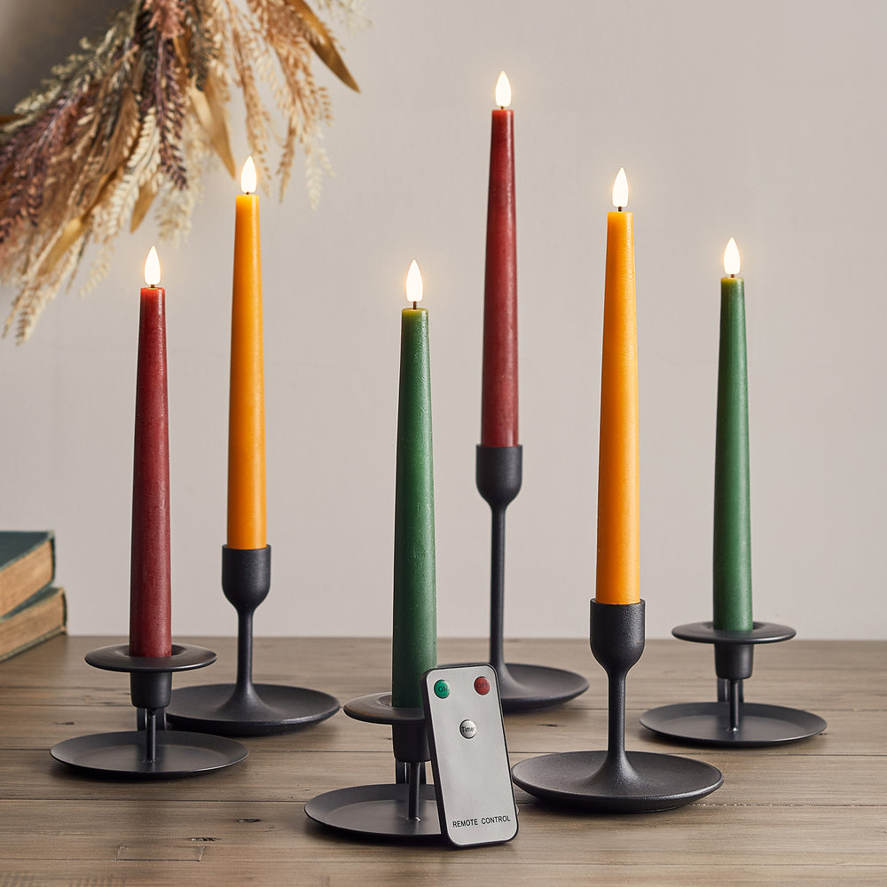 Sechs brennende LED Stabkerzen in Herbstfarben mit Fernbedienung auf Holztisch