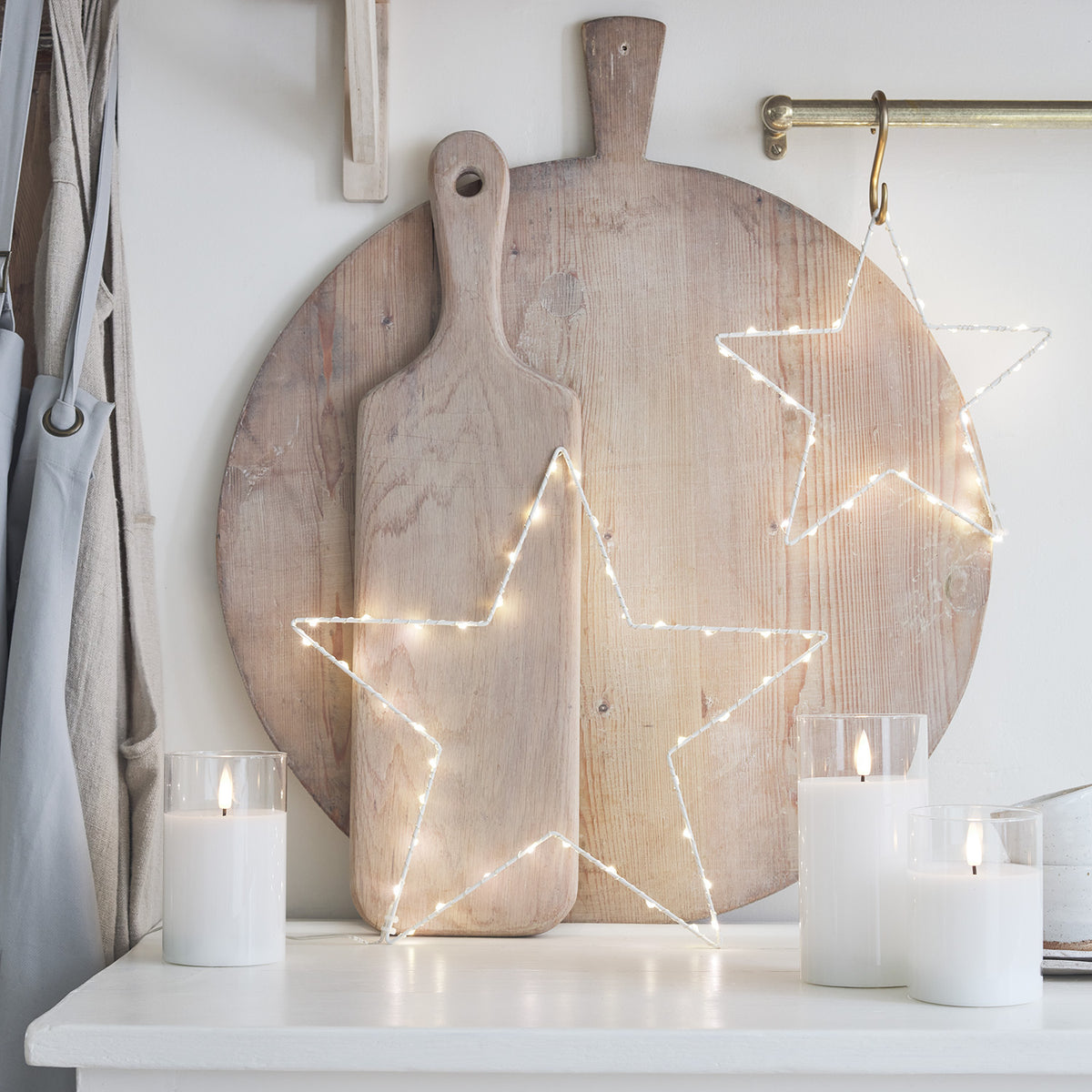 LED-Kerzen Trio mit Stern-Lichterkette und Holzbrett als Hintergrund