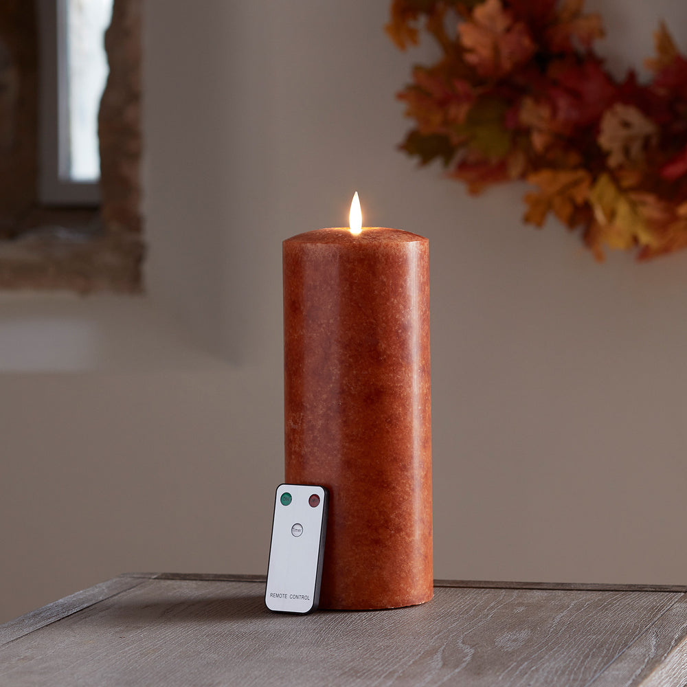 Orangefarbene LED Stumpenkerze aus Echtwachs mit Fernbedienung auf Holztisch