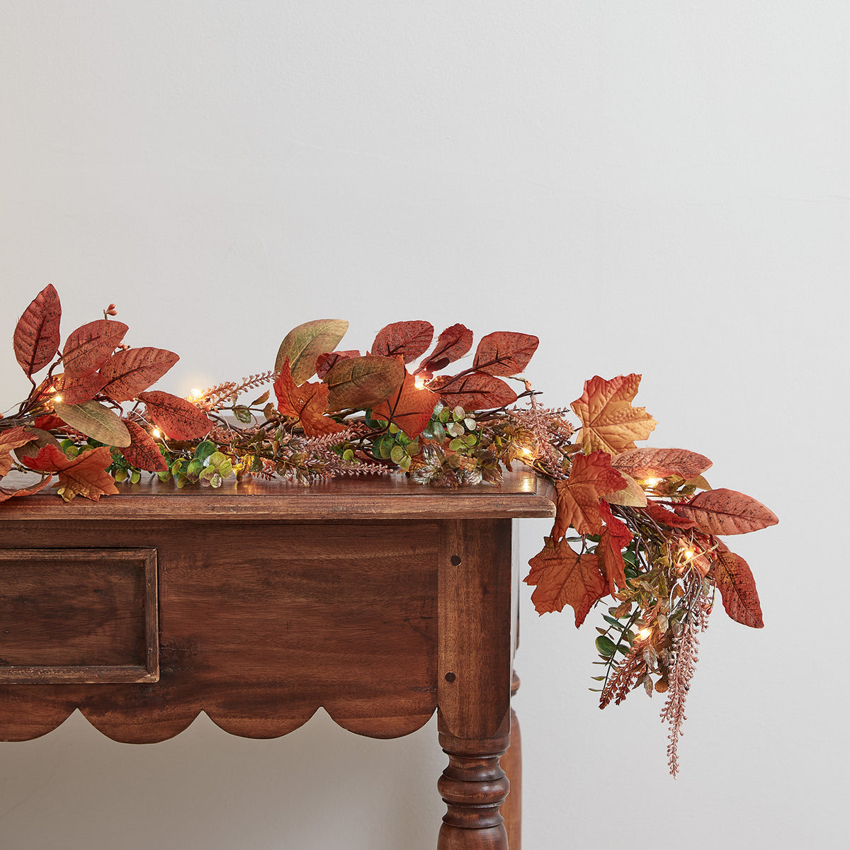 Herbstliche 2m Girlande mit bunten Ahornblättern und warmweißer Micro Lichterkette auf einem Holztisch