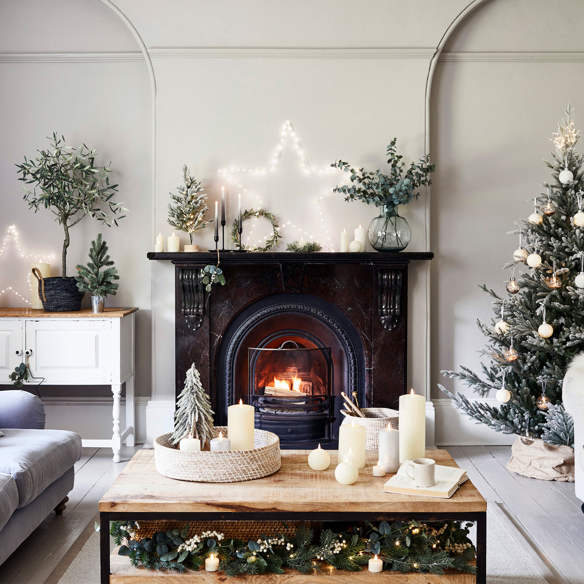 Weihnachtlich dekoriertes Wohnzimmer mit Kamin, Tannenbaum und beleuchteter Girlande