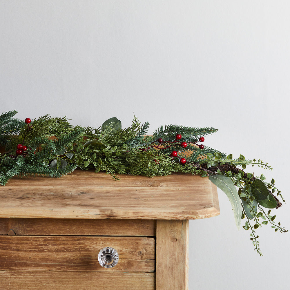 Nahaufnahme der roten Beeren und grünen Zweige der beleuchteten Weihnachtsgirlande