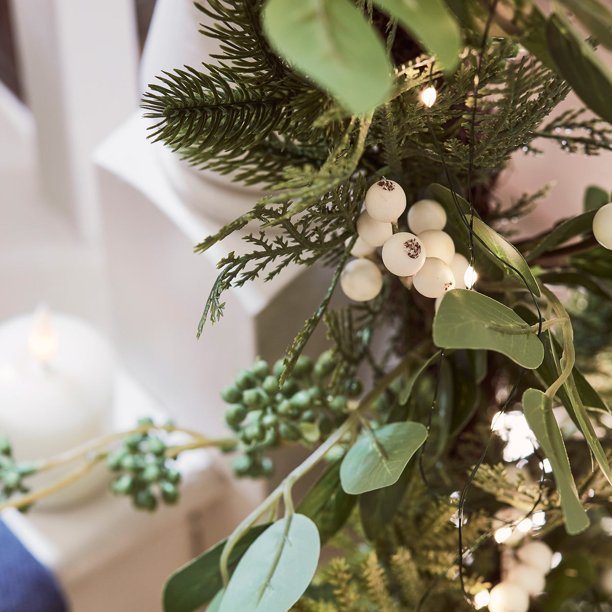 Detailaufnahme der weißen Beeren und grünen Blätter der beleuchteten Weihnachtsgirlande