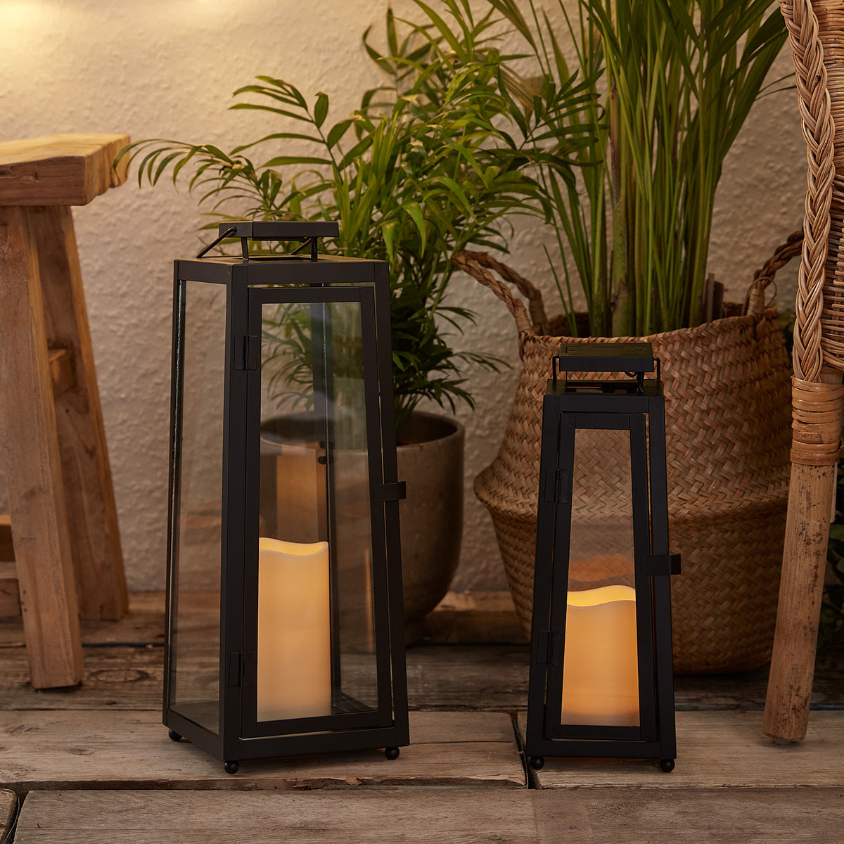 Solar-Laternen Duo mit warmweiß flackernden LED-Kerzen auf Holzterrasse neben Pflanzen und Korb