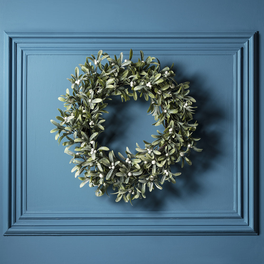Mistelzweig Weihnachtskranz mit weißen Beeren ohne Beleuchtung an blauer Wand
