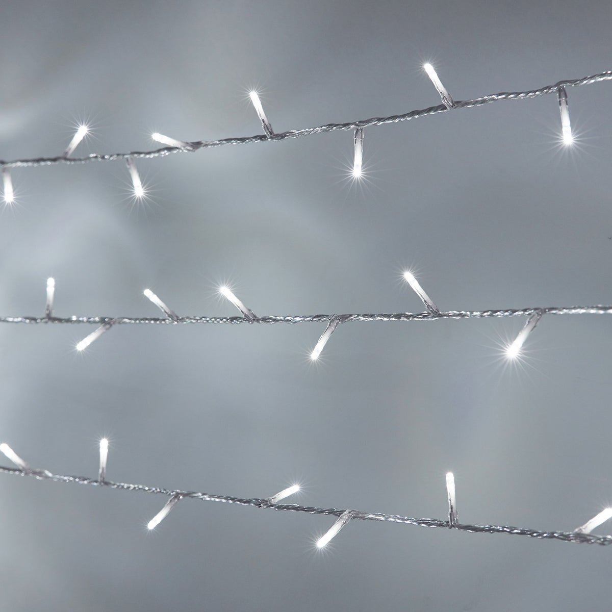 Weiße LED-Lichterkette mit transparentem Kabel, leuchtende kleine Lämpchen auf grauem Hintergrund