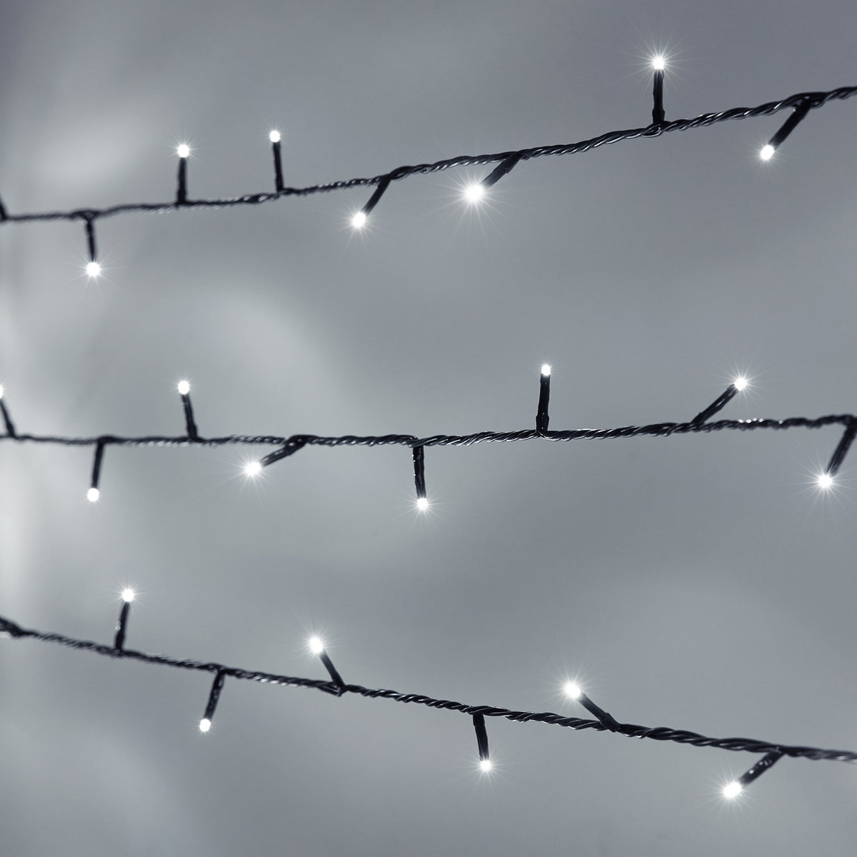 Nahaufnahme weiße LED-Lichterkette mit grünem Kabel vor grauem Hintergrund