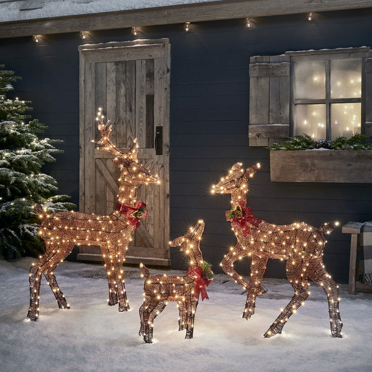 3er Set braune LED-Rentierfamilie mit Hirsch, Hirschkuh und Rehkitz vor Holztür im Schnee