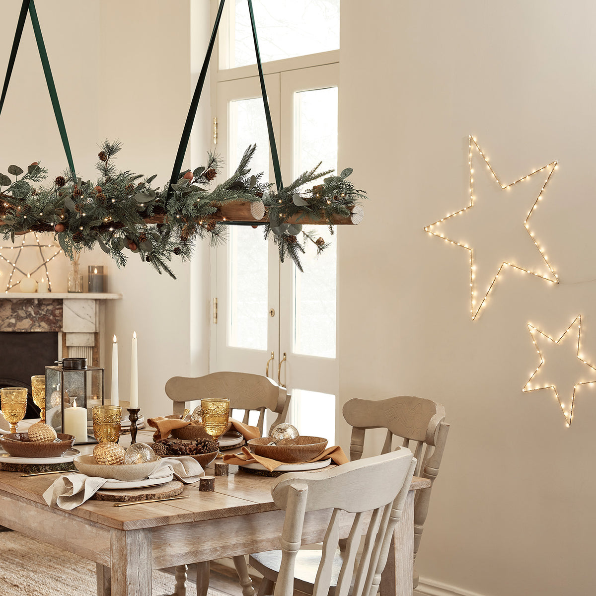 Weihnachtliche Girlande mit Beleuchtung auf dunklem Holztisch vor beiger Wand