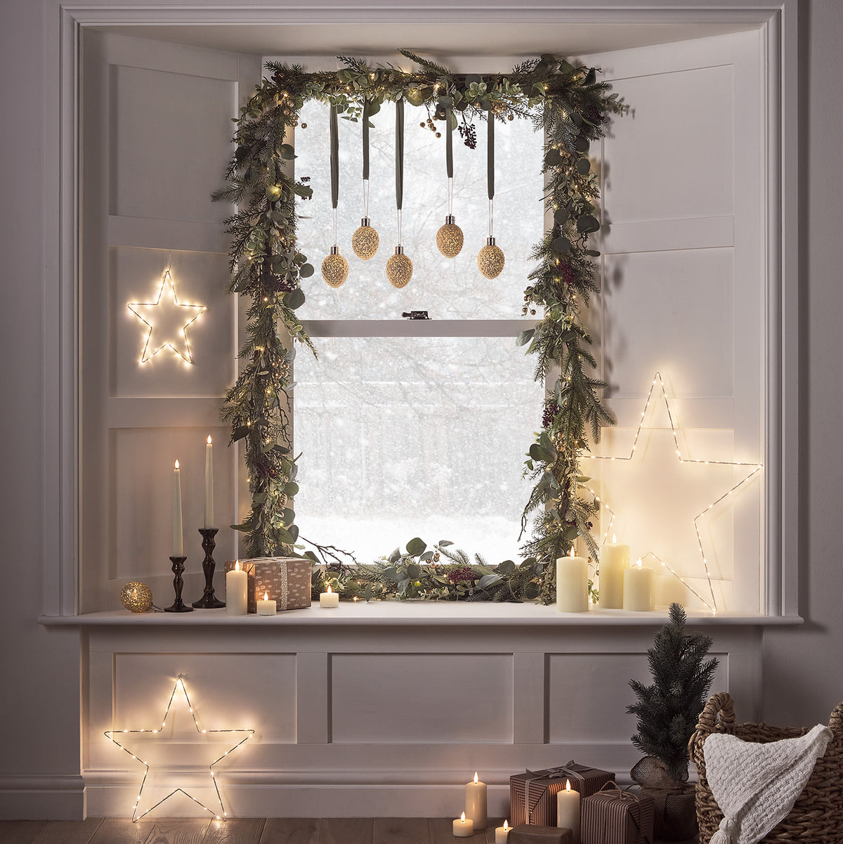 Weihnachtlich dekorierter Kaminsims mit LED-Sternen, grünen Zweigen und goldenen Kugeln