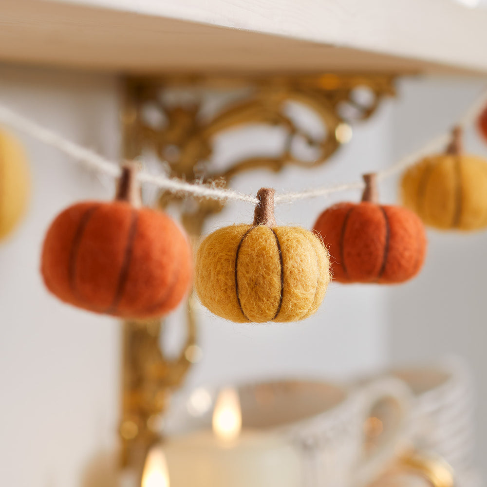 Herbstgirlande mit kleinen Filzkürbissen in Orange- und Brauntönen an einer Schnur hängend
