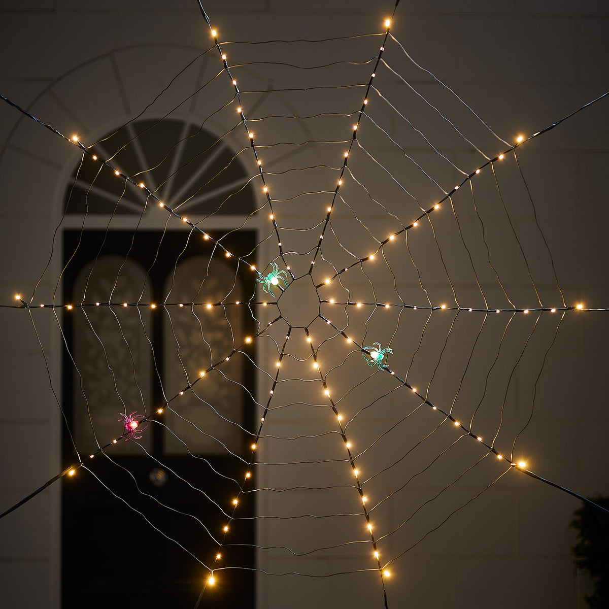 LED-Spinnweben-Deko mit warmweißen Lichtern und drei bunten Spinnen vor dunklem Hintergrund