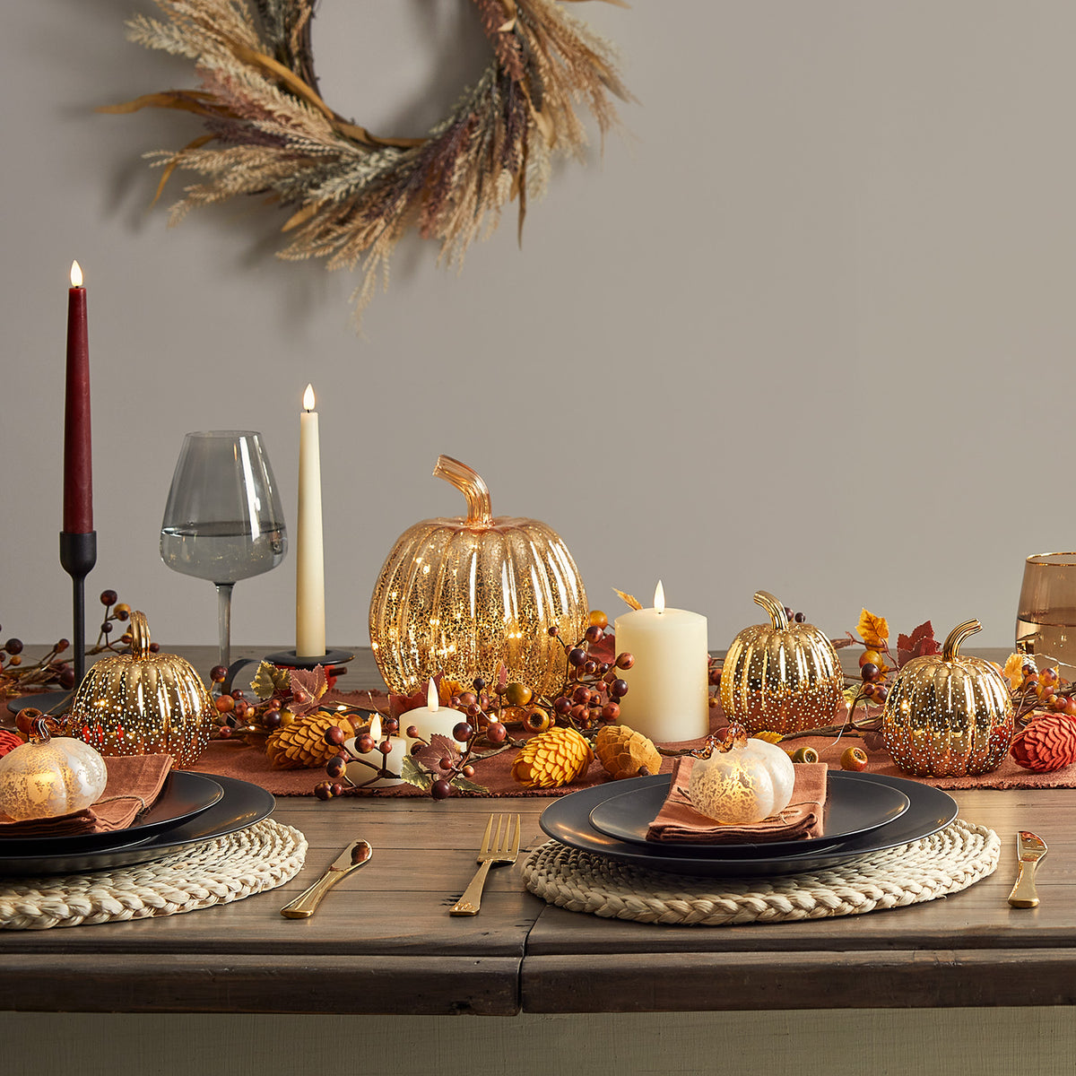 Herbstlich dekorierter Esstisch mit LED Stabkerzen, goldenen Kürbissen und herbstlichen Accessoires