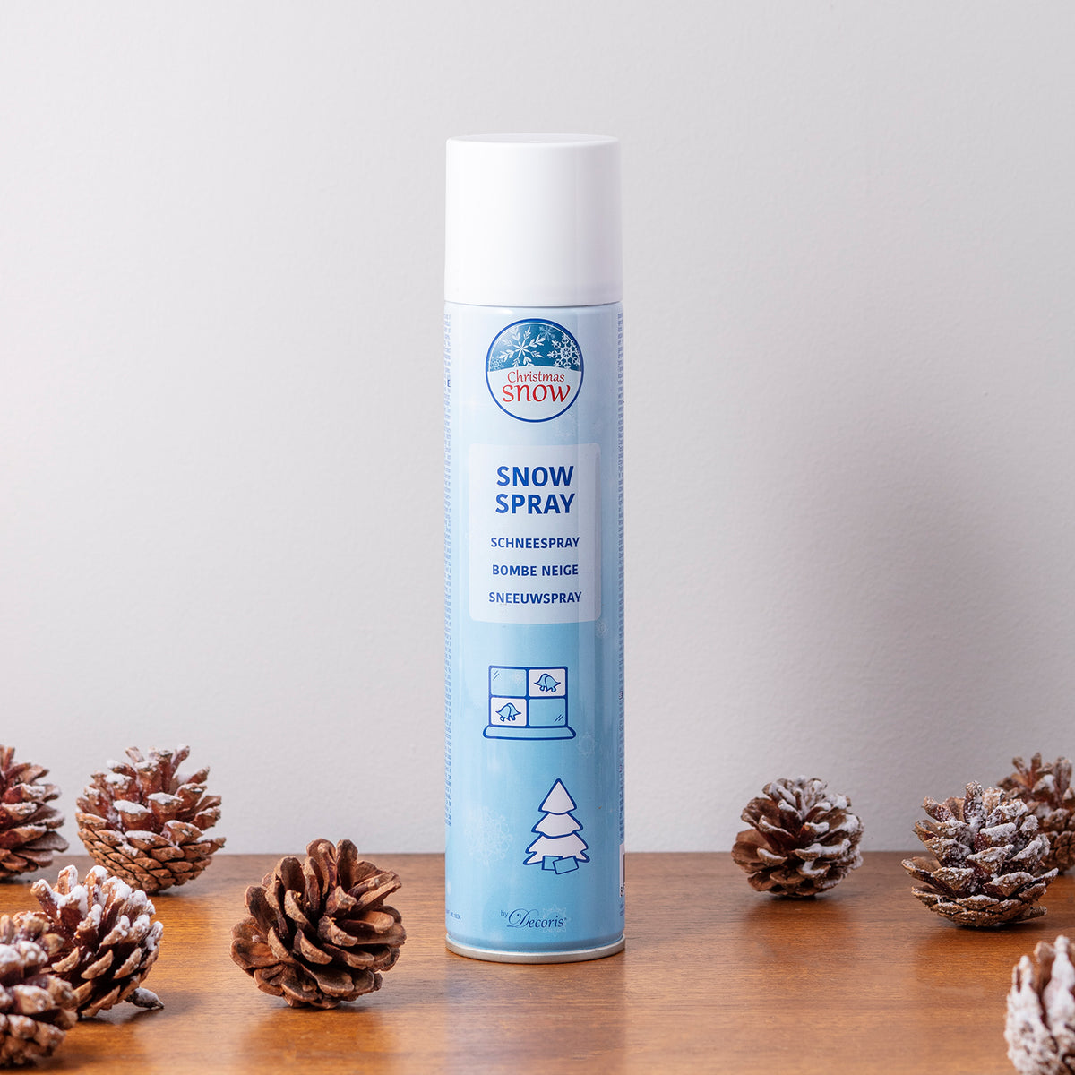 Dose Schneespray auf Holztisch umgeben von Tannenzapfen mit Kunstschnee