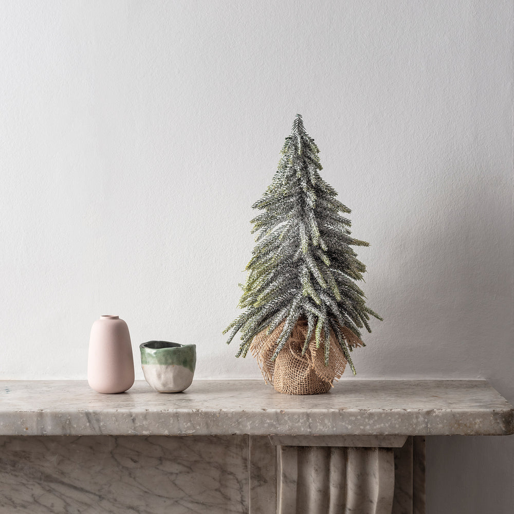 35cm hoher Mini Weihnachtsbaum mit Schneebesatz neben zwei Keramikvasen auf Marmorplatte