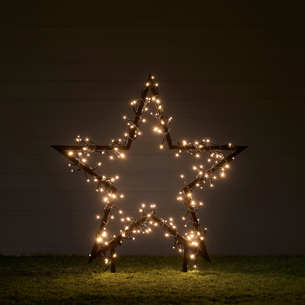 60cm großer schwarzer Stern mit warmweißen LED-Lichtern auf Rasen im Dunkeln