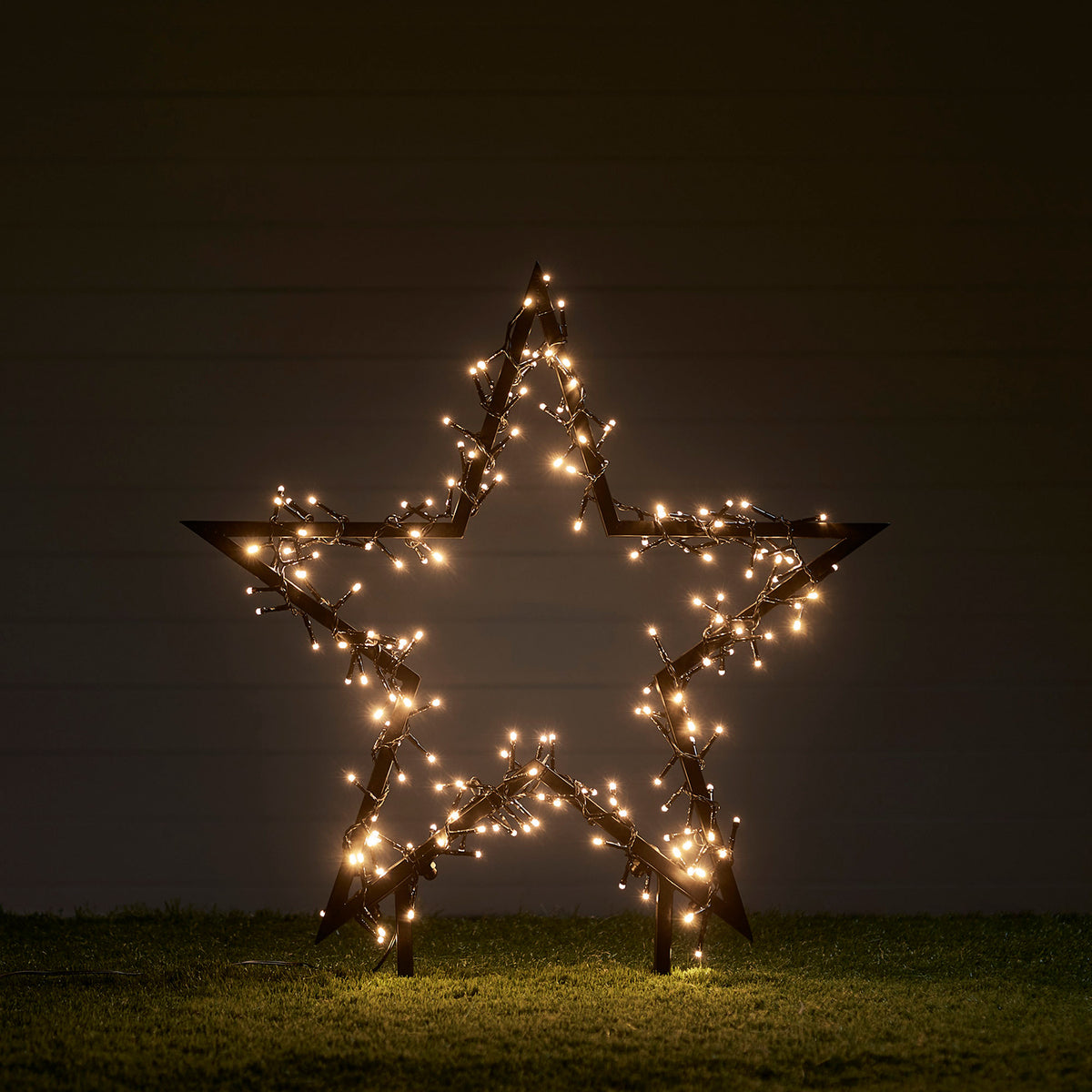 60cm großer schwarzer Stern mit warmweißen LED-Lichtern auf Rasen im Dunkeln