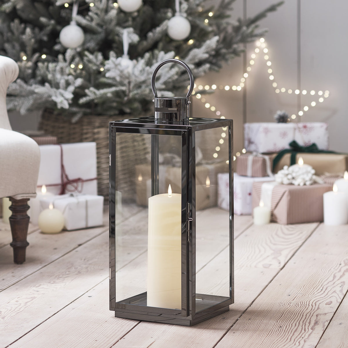 Große LED-Laterne vor Weihnachtsbaum und Geschenken auf hellem Holzboden im Wohnzimmer