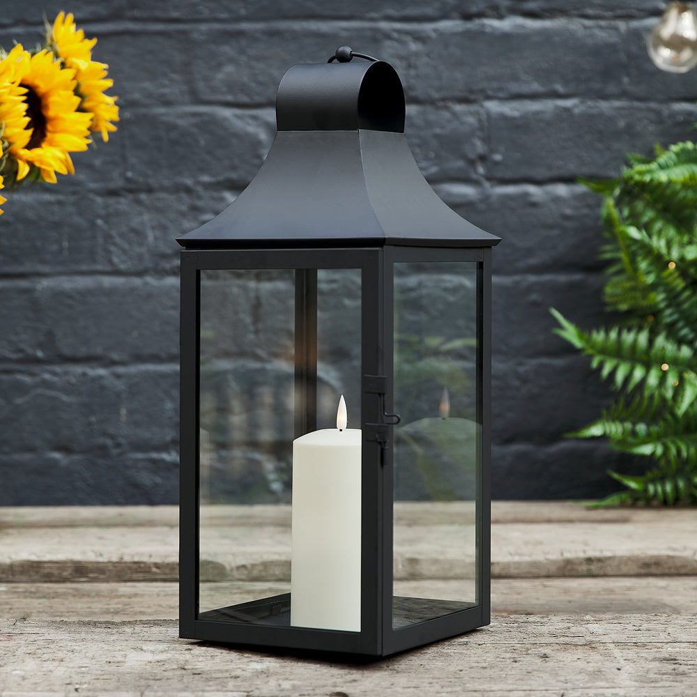 Nahaufnahme der schwarzen Albury Gartenlaterne mit realistischer LED-Kerze vor dunkler Wand