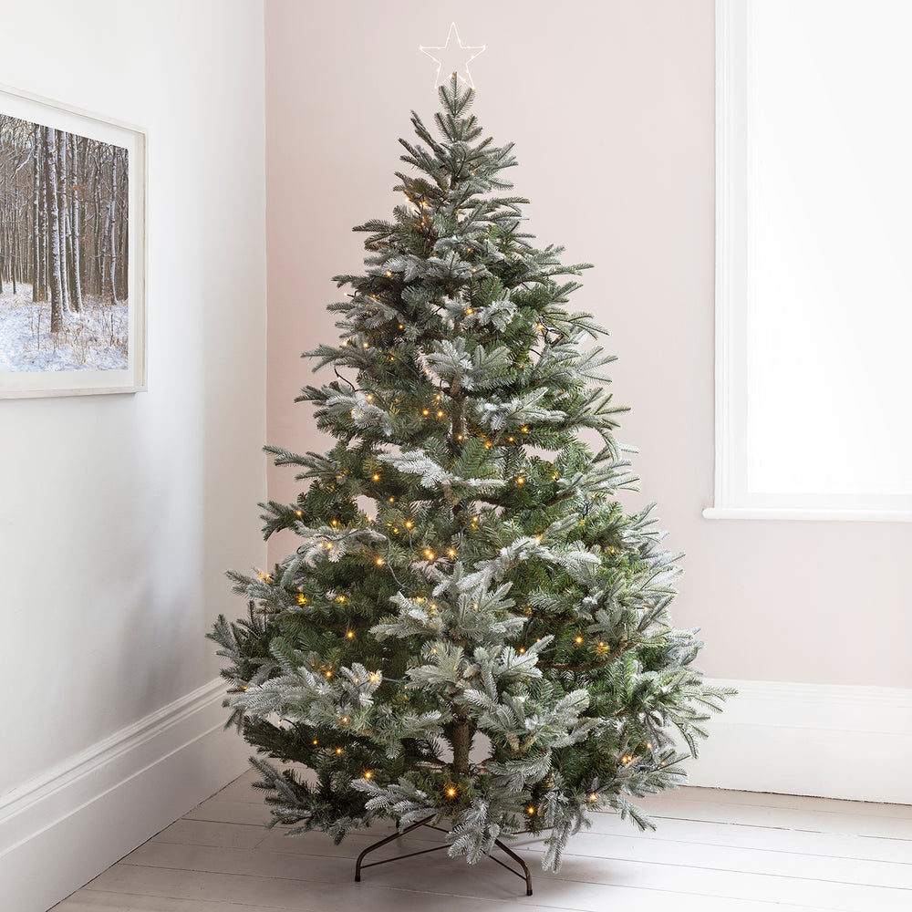 Weihnachtsbaum mit LED Stern als Spitze und warmweißen Lichtern in hellem Raum