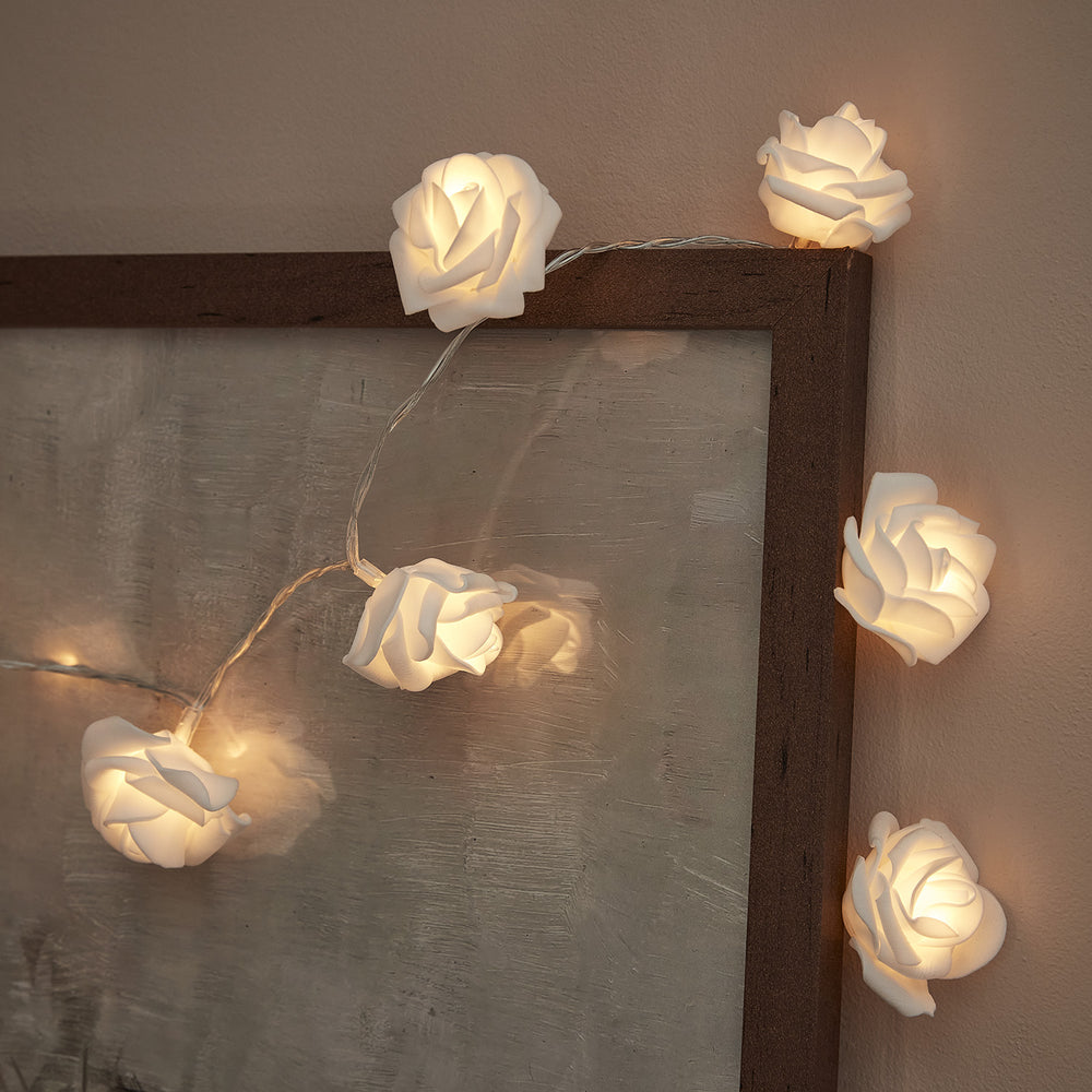 Weiße Rosen Lichterkette mit warmweißen LEDs um einen Bilderrahmen drapiert
