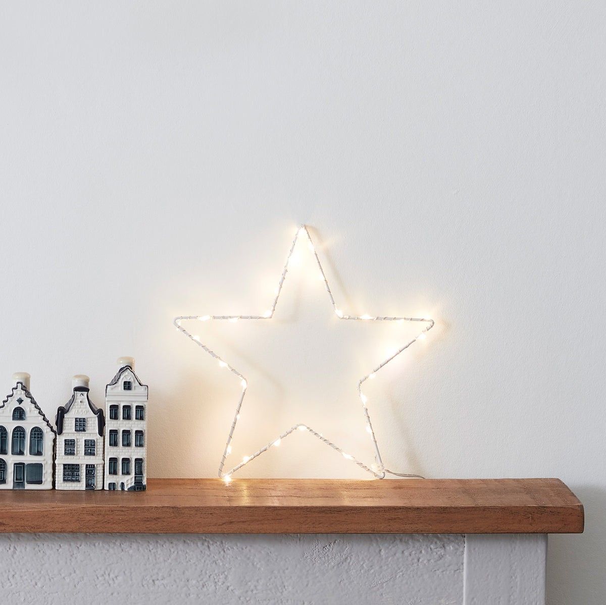 LED Stern mit warmem Licht auf Kaminsims mit Kerzen und Weihnachtsdeko