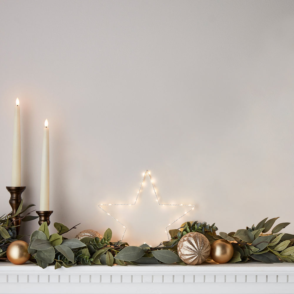 Leuchtender LED Stern auf Kaminsims mit Kerzen und Weihnachtsdeko