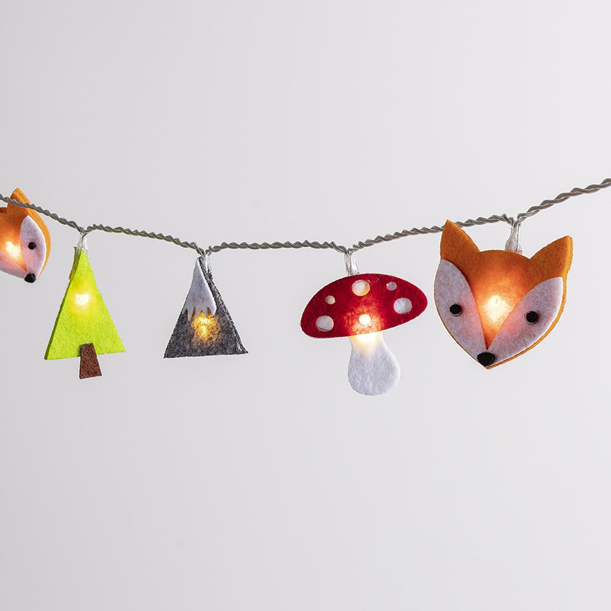 Nahaufnahme der Wald-Lichterkette mit leuchtenden Filzfiguren Fuchs, Pilz, Baum und Berg