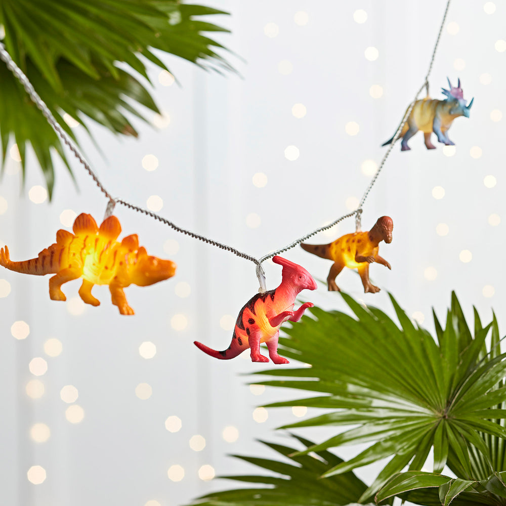 Bunte Dinosaurier Lichterkette mit leuchtenden Figuren vor grünem Blatt
