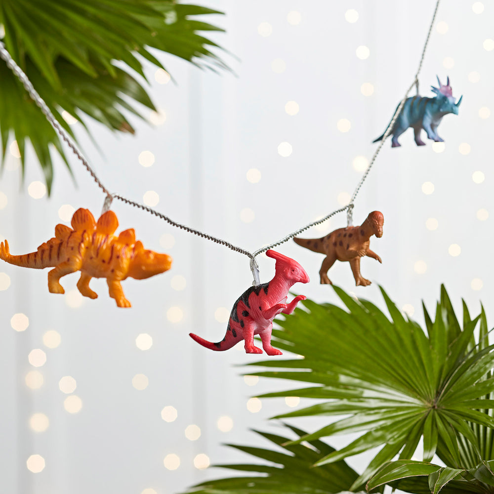 Bunte Dinosaurier Lichterkette ohne Beleuchtung vor grünem Blatt
