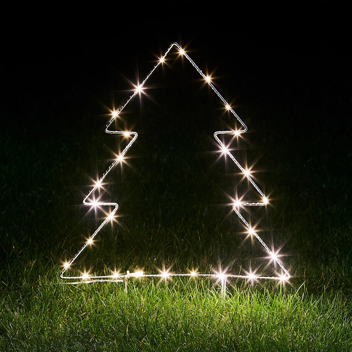 Leuchtender Micro LED Tannenbaum aus Metallrahmen auf Gras bei Nacht