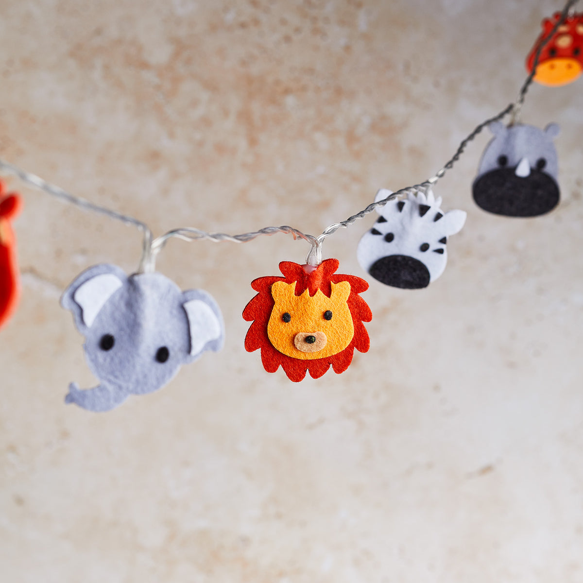 Safari-Filztiere Löwe, Elefant, Zebra und Nashorn an transparenter Lichterkette ohne Beleuchtung
