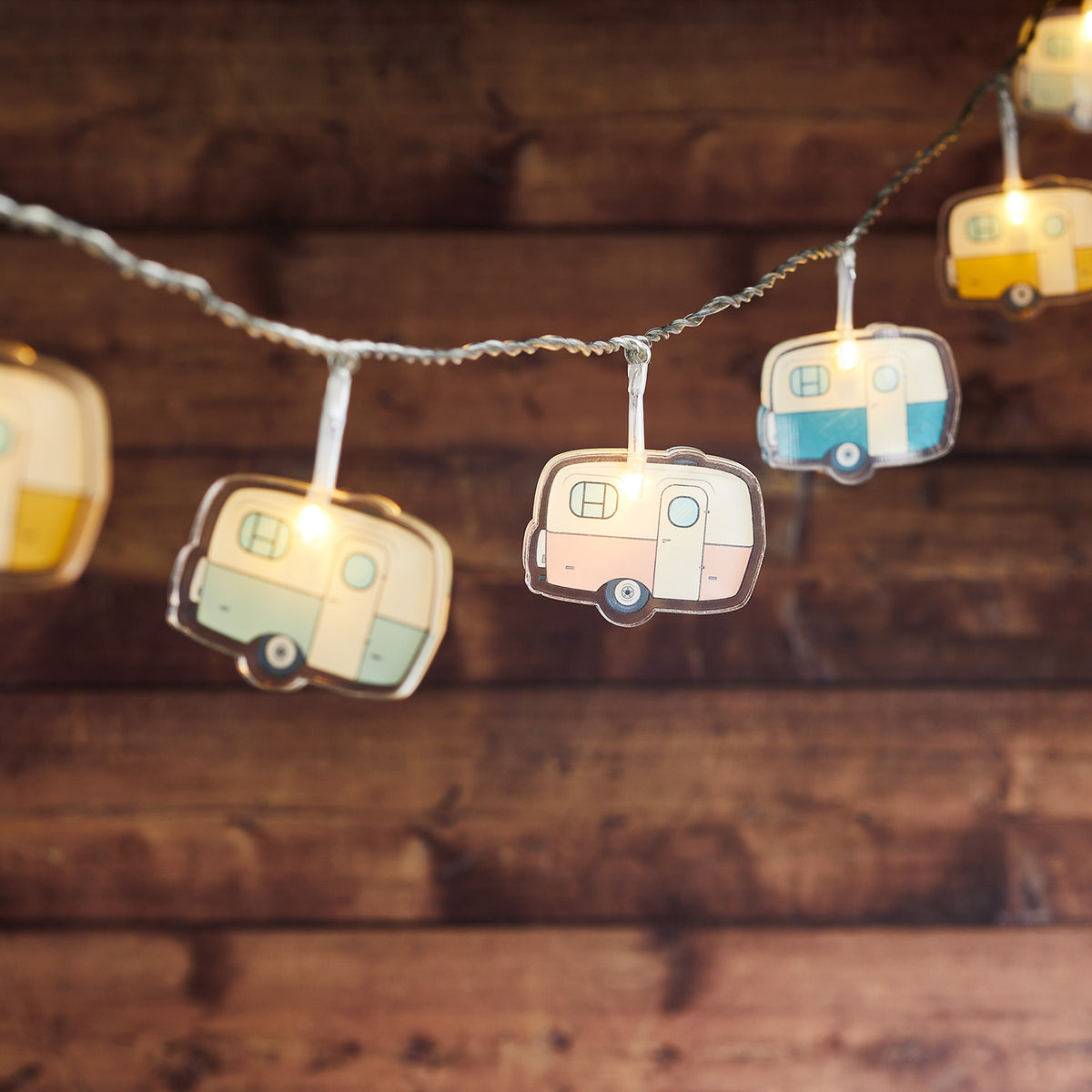 Lichterkette mit 12 bunten Retro-Campingwagen aus Acryl, warmweiß beleuchtet vor Holzwand