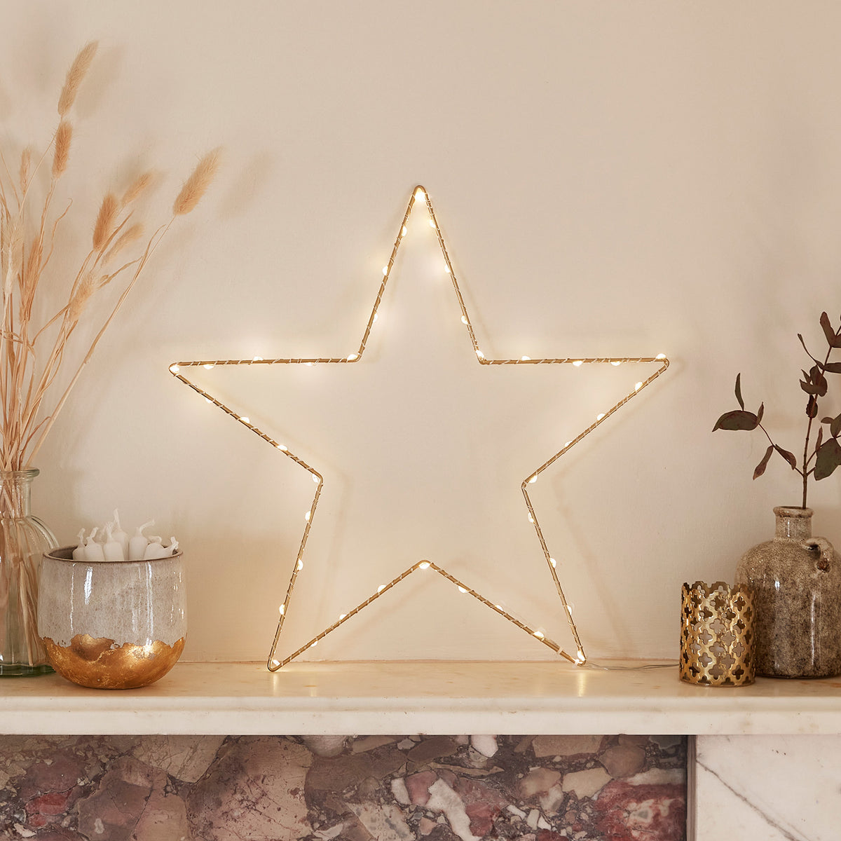 Goldener Osby LED Stern mit warmweißen Micro LEDs auf Kaminsims dekoriert