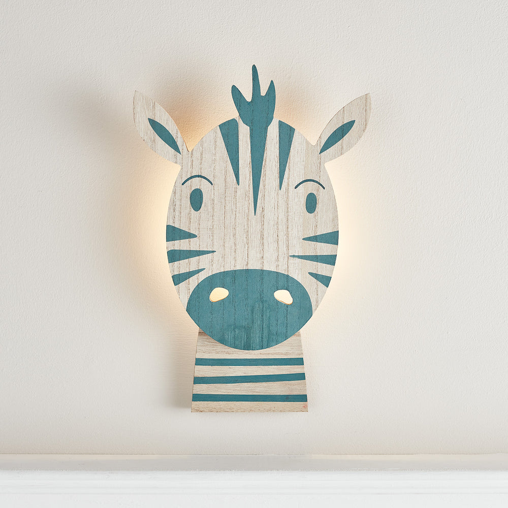 Holzlampe in Form eines Zebrakopfes mit blauen Streifen und warmweißem Licht an der Wand