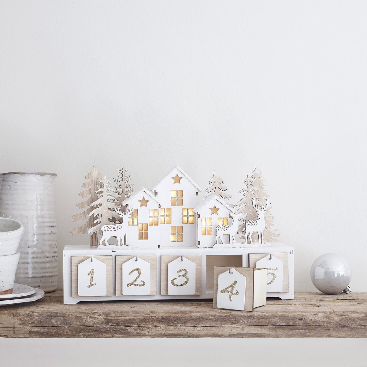 Adventskalender mit herausgezogener Schublade und goldglitzernder Zahl 4 auf Holzuntergrund