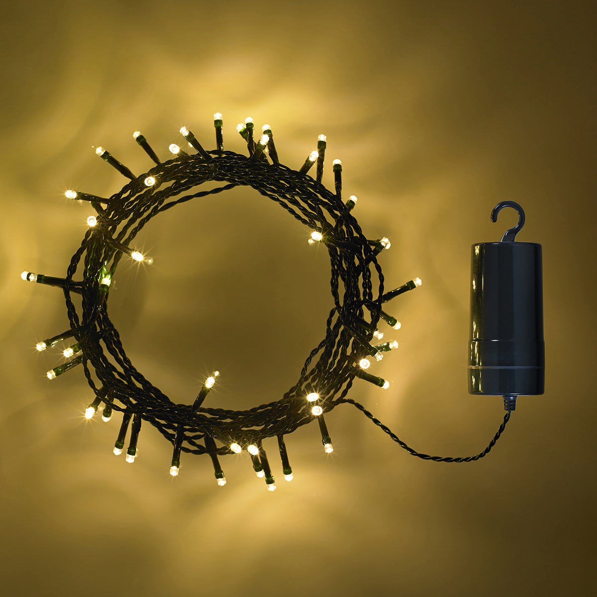 Aufgerollte LED-Lichterkette mit warmweißen LEDs und Batteriebox vor gelbem Hintergrund