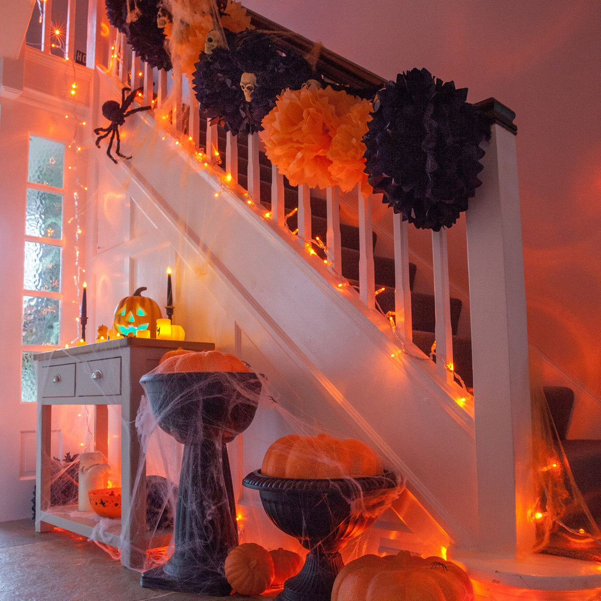 Halloween-Dekoration mit orangener LED-Lichterkette an Treppe und Kürbissen