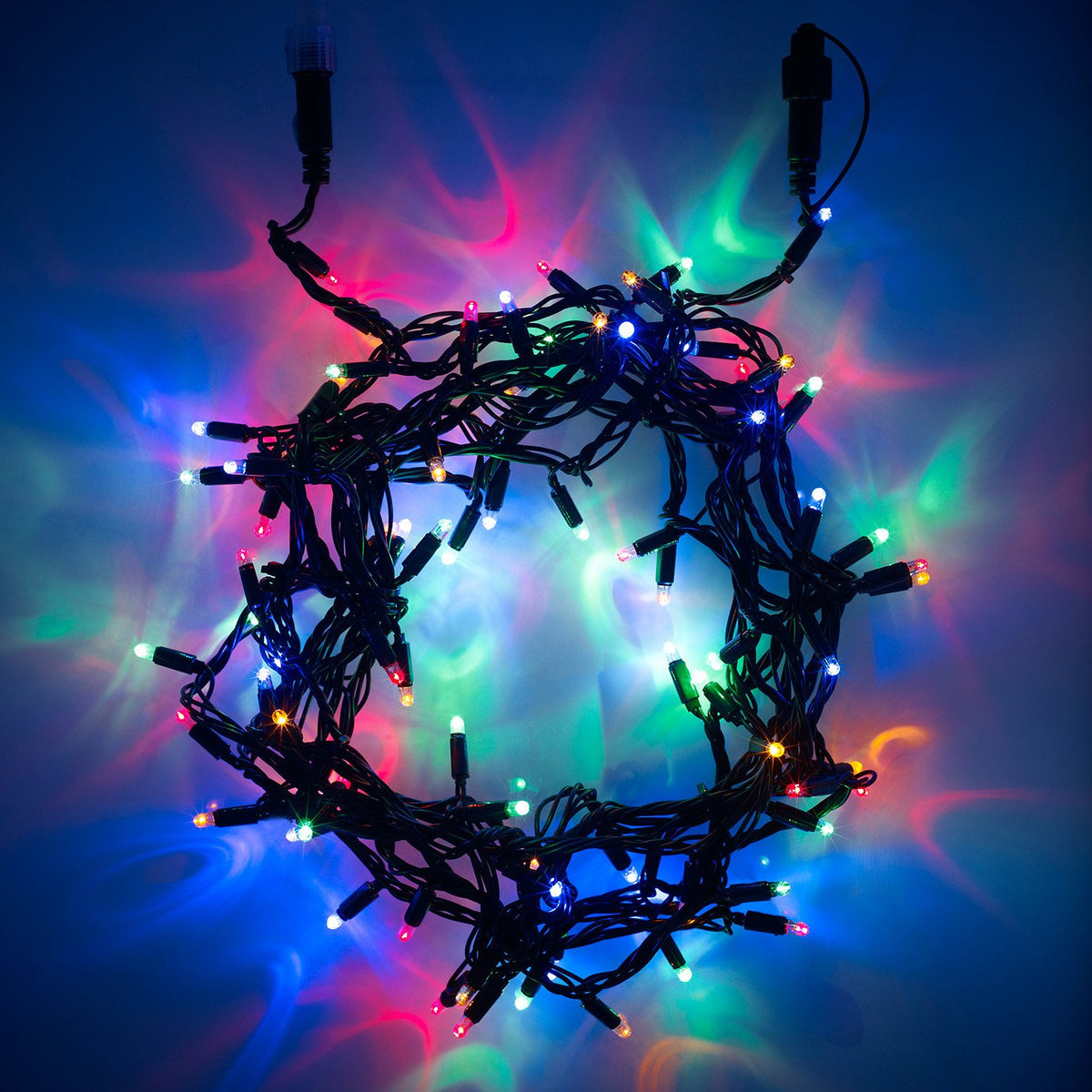 Bunte LED-Lichterkette mit grünem Kabel leuchtet im Dunkeln mit roten, blauen und grünen Lichtern