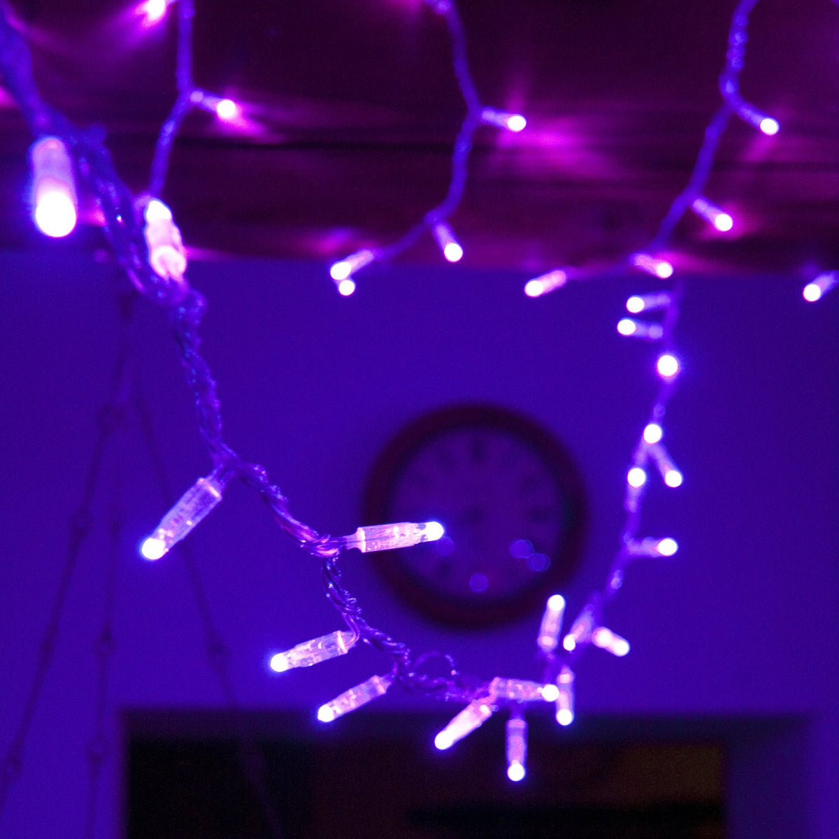 Lila LED-Lichterkette dekorativ an Holzbalken mit Kerzenhalter im Raum