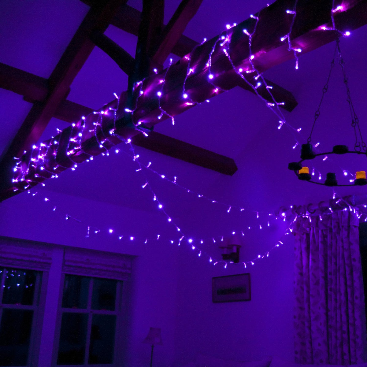 Lila LED-Lichterkette mit Spinnennetz-Dekoration an Holzbalken